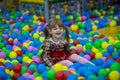 Happy little kid girl in red dress play in pool with colorful plastic balls Royalty Free Stock Photo