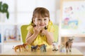 Happy little kid girl. Smiling child toddler plays animal toys at home or kindergarten Royalty Free Stock Photo