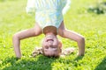 Happy little girl standing on her head on green lawn. Royalty Free Stock Photo