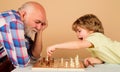 Happy little kid playing chess with grandpa. Family relationship with grandfather and grandson. Granddad and grandchild Royalty Free Stock Photo