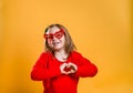 Happy little kid on valentines day. Funny girl make heart from hands isolated on yellow background. Stylish child in red Royalty Free Stock Photo