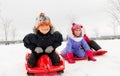 Happy little kids sliding down on sleds in winter
