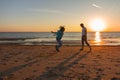 Happy little laughing girl 7 years jumping on the beach playing with dad at sunset Royalty Free Stock Photo