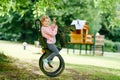 Happy little preschool girl having fun on swing in domestic garden. Healthy toddler child swinging on summer day Royalty Free Stock Photo