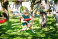 Happy little preschool girl having fun on swing in domestic garden. Healthy toddler child swinging on sunny summer day Royalty Free Stock Photo