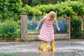 Happy little preschool girl wearing yellow rain boots and walking during puddles. Cute child in colorful clothes jumping Royalty Free Stock Photo