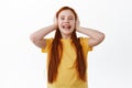 Happy little redhead girl with freckles laughing, smiling and covering ears with hands, unwilling to listen, playing Royalty Free Stock Photo