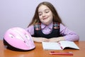 Happy little school girl doing homeworks at desk