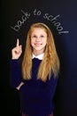 Happy little school girl near school blackboard