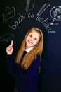 Happy little school girl near school blackboard