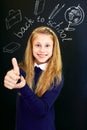 Happy little school girl near school blackboard. Gesture ok