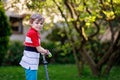 Happy little school kid boy riding on scooter on way to elementary school. Child without safety helmet, school bag on Royalty Free Stock Photo