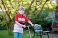 Happy little school kid boy riding on scooter on way to elementary school. Child without safety helmet, school bag on Royalty Free Stock Photo