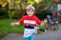 Happy little school kid boy riding on scooter on way to elementary school. Child without safety helmet, school bag on Royalty Free Stock Photo
