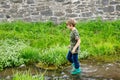 Happy little school kids boy having fun walking through water in river in gum rubber boots. child portrait of healthy Royalty Free Stock Photo