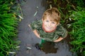 Happy little school kids boy having fun walking through water in river in gum rubber boots. child portrait of healthy Royalty Free Stock Photo