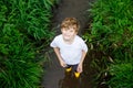 Happy little school kids boy having fun walking through water in river in gum rubber boots. child portrait of healthy Royalty Free Stock Photo
