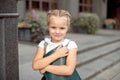 Happy little schoolgirl with book going back to school outdoor.