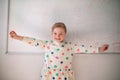 Happy little schoolgirl with down syndrome standing in front of whiteboard and looking at camera Royalty Free Stock Photo