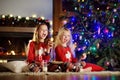 Happy little sisters having milk and cookies by a fireplace in a cozy dark living room on Christmas eve