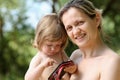 Happy little smiling child in the arms of the mother on a natural background Royalty Free Stock Photo