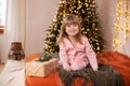 Happy little smiling girl in pajamas with gift on xmas Eve lies on bed. child opens New year gift at home near christmas tree with Royalty Free Stock Photo