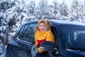 Happy little smilling boy look from a car window on a sunny day at winter snowy forest