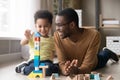 Happy little son playing with black dad using wooden blocks Royalty Free Stock Photo