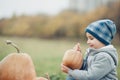 Happy little toddler boy on pumpkin patch on cold autumn day, with a lot of pumpkins for halloween or thanksgiving Royalty Free Stock Photo