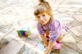 Happy little toddler girl drawing with colorful chalks on ground or asphalt in summer. Excited child having fun with Royalty Free Stock Photo