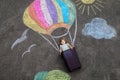 Happy little toddler girl flying in hot air balloon painted with colorful chalks in rainbow colors on ground or asphalt