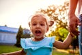 Happy little toddler girl laughing and screaming outdoors. Mother holding her daughter`s hand in park. Family time Royalty Free Stock Photo