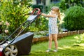 Happy little toddler girl with lawn mower. Preschool child cut the lawn and help the family. Portrait of toddler working Royalty Free Stock Photo