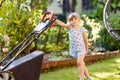 Happy little toddler girl with lawn mower. Preschool child cut the lawn and help the family. Portrait of toddler working Royalty Free Stock Photo