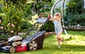 Happy little toddler girl with lawn mower. Preschool child cut the lawn and help the family. Portrait of toddler working Royalty Free Stock Photo