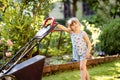 Happy little toddler girl with lawn mower. Preschool child cut the lawn and help the family. Portrait of toddler working Royalty Free Stock Photo