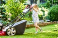 Happy little toddler girl with lawn mower. Preschool child cut the lawn and help the family. Portrait of toddler working Royalty Free Stock Photo