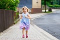 Happy little toddler girl running on street in the city, outdoors. Funny preschool child hild having fun with running