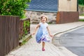 Happy little toddler girl running on street in the city, outdoors. Funny preschool child hild having fun with running