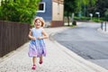 Happy little toddler girl running on street in the city, outdoors. Funny preschool child hild having fun with running