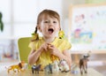 Happy little toddler plays animal toys at home or daycare centre