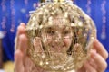 Happy little 10 years girl looking at camera through a christmas ball in festive  decorated home interrior Royalty Free Stock Photo