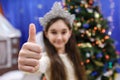 Happy little 10 years girl show thumb up, sign ok, looking at camera in christmas decorated home indoor Royalty Free Stock Photo