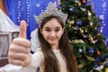 Happy little 10 years girl show thumb up, sign ok, looking at camera in christmas decorated home indoor Royalty Free Stock Photo