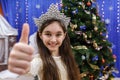 Happy little 10 years girl show thumb up, sign ok, looking at camera in christmas decorated home Royalty Free Stock Photo