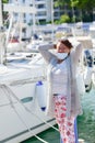 Happy looking asian woman fixing her surgical mask behind her head outdoors on an out of focus harbor background Royalty Free Stock Photo