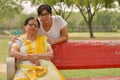 Happy looking young Indian woman with her mother sitting on a red bench in a park in New Delhi, India. Concept Mother`s day Royalty Free Stock Photo