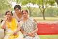 Happy looking young Indian woman with two senior Indian mother / mother in law sitting on a red bench in a park in New Delhi, Royalty Free Stock Photo