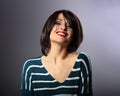 Happy loudly laughing with wide smile young woman with short hair in fashion sweater. portrait on grey background