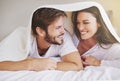 Happy, love and couple in conversation with blanket for relaxing, bonding and resting on bed together. Happy, romantic Royalty Free Stock Photo